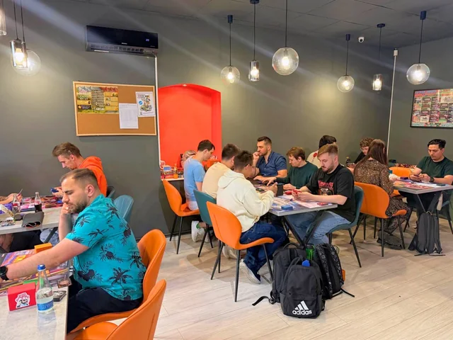Card games at tables with orange chairs inside KRIT Brașov