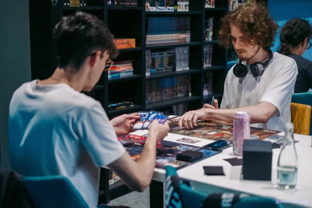 Two players in a card game beside the shelves at KRIT Ploiești